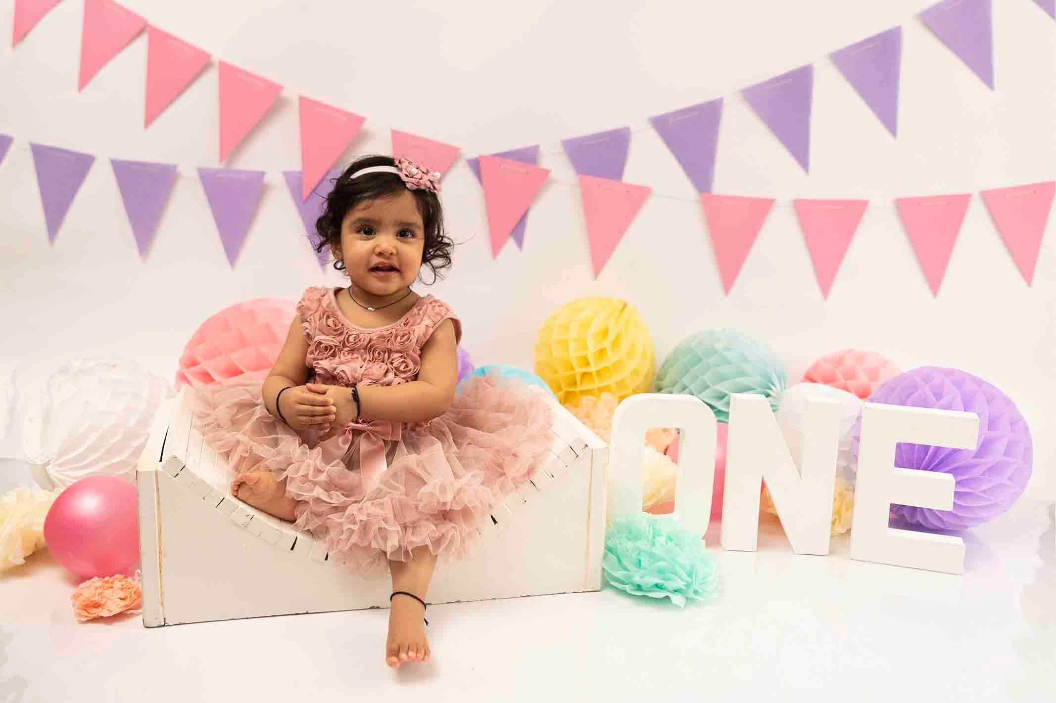 baby girl siting on bench at cake smash photo session