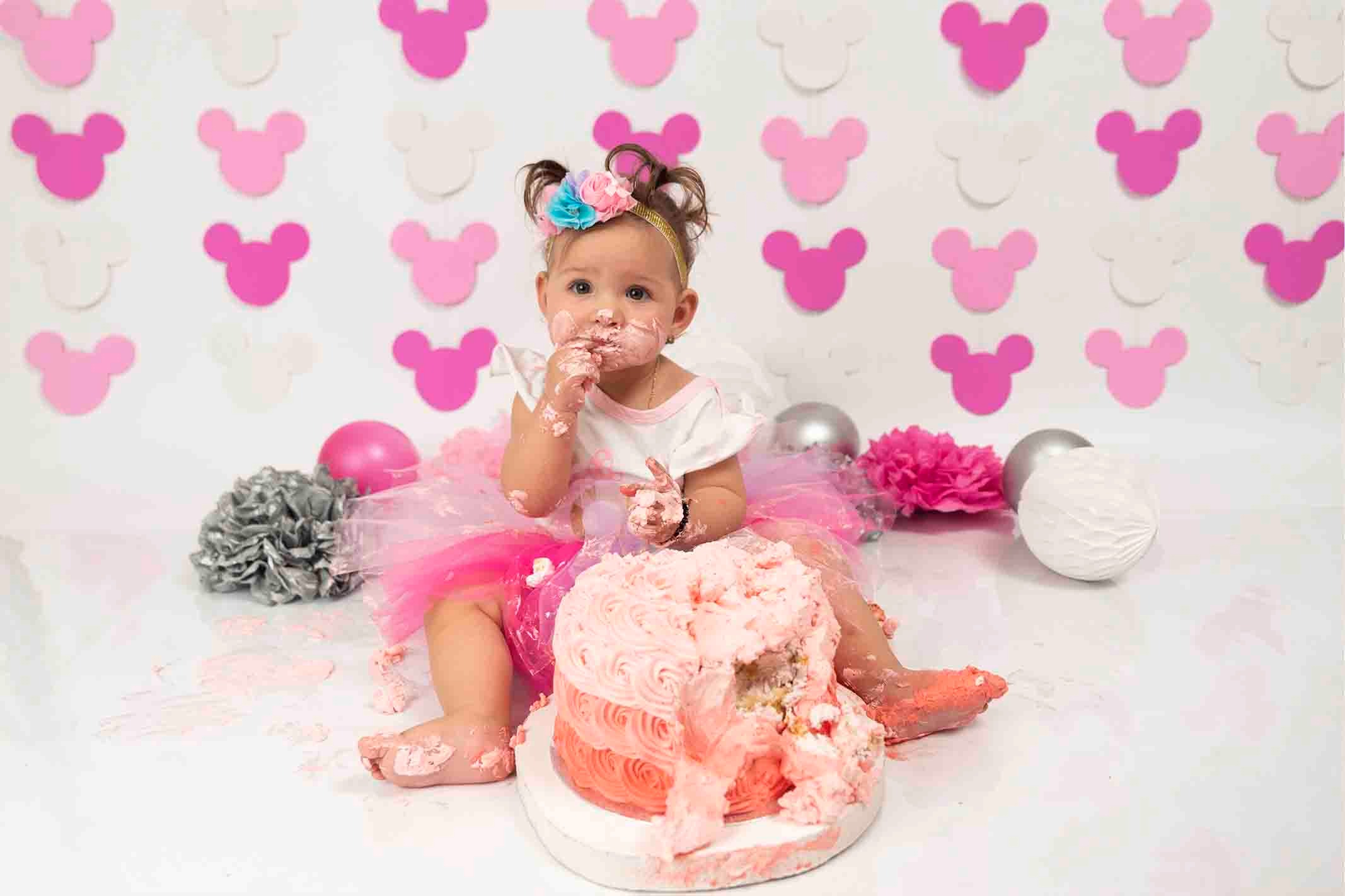 Cake smash photographer with girl tastig cake