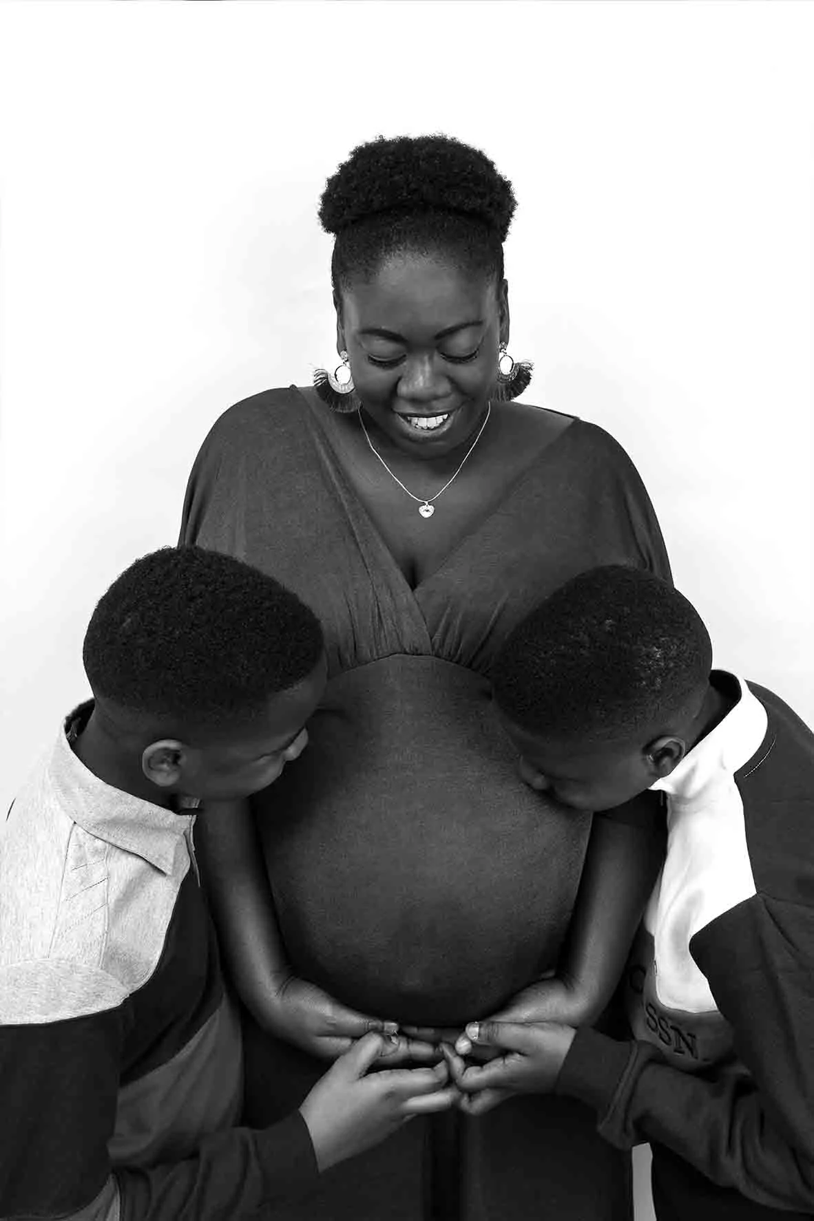 Maternity photos with brothers kissing baby bump