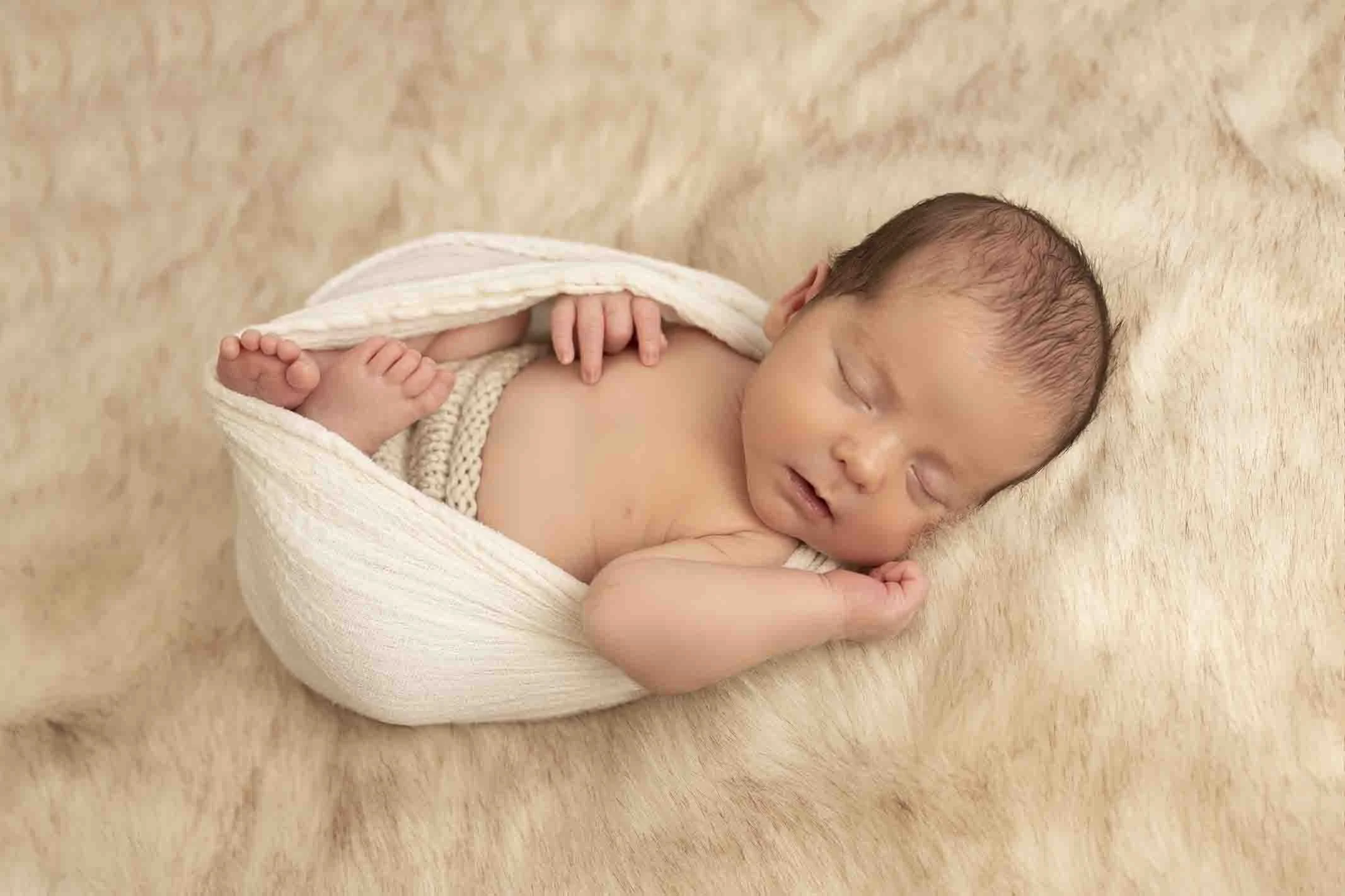 Newborn photographer taking photos on baby in white furr