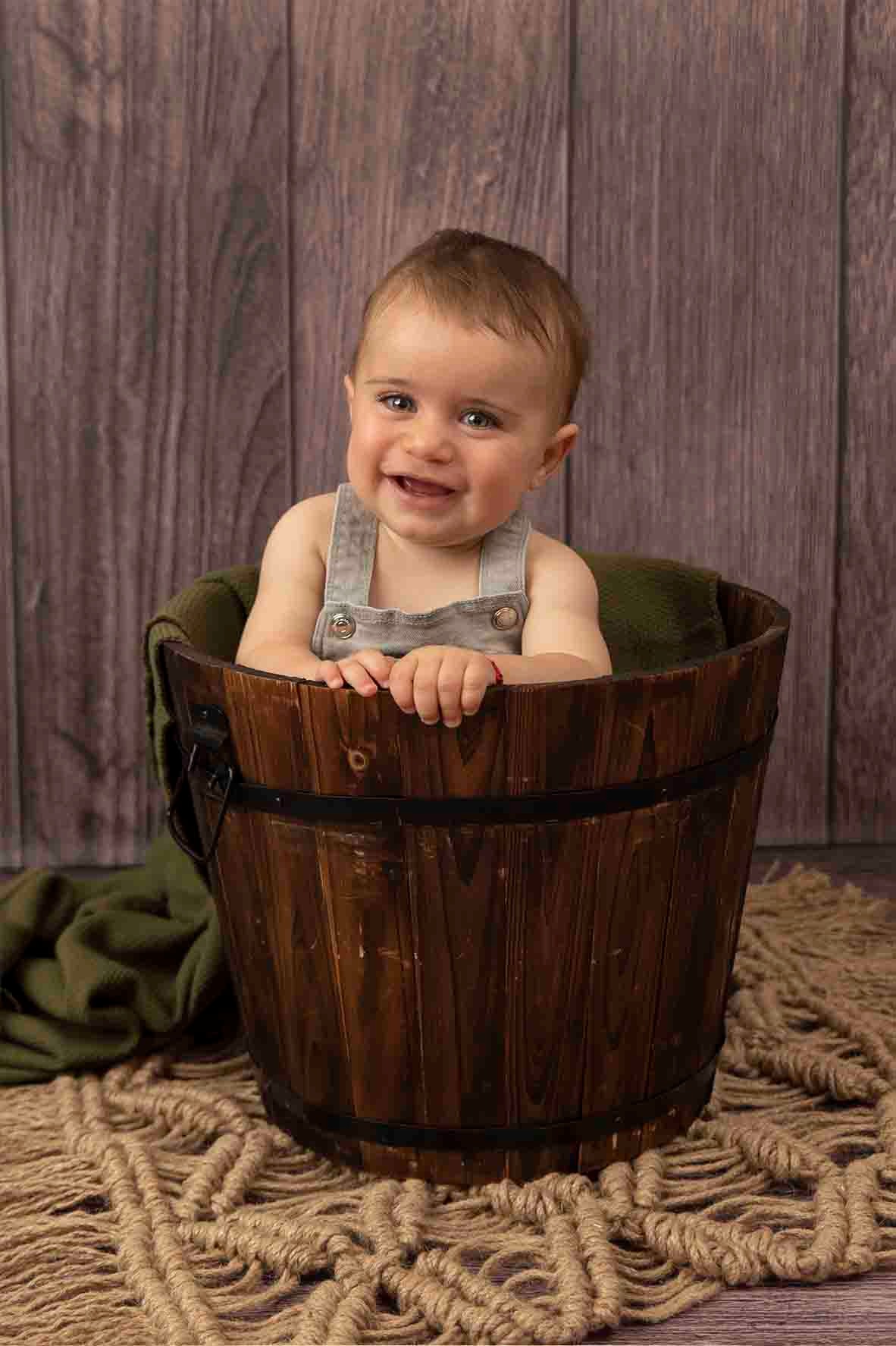 baby boy in wooden bucket at baby photoshoot