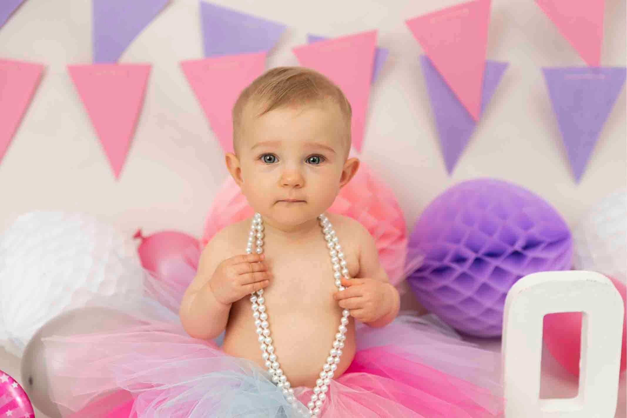 baby girl wearing pearls at cake smash photoshoot