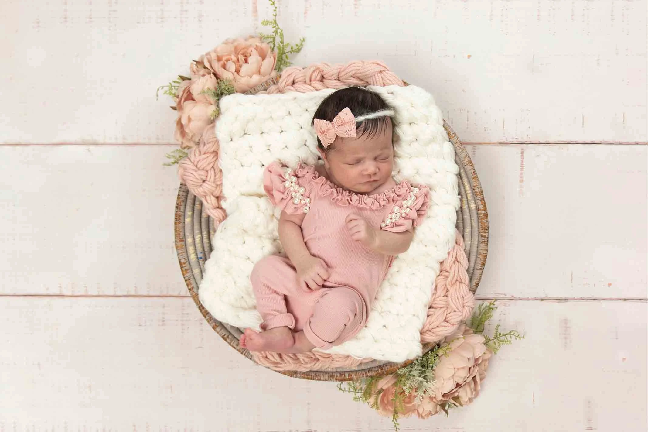 newborn girl in basket on wooden background