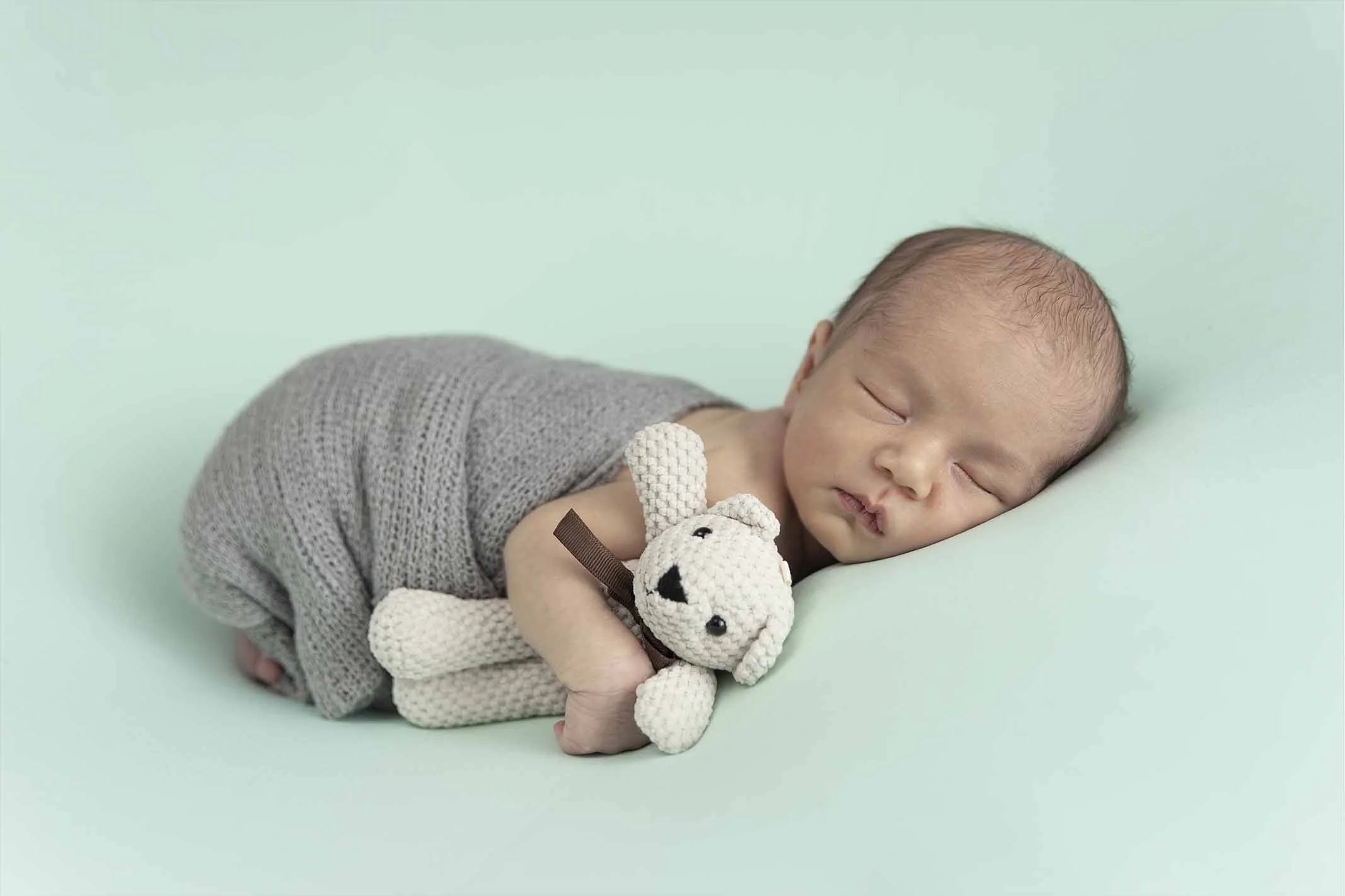 newborn holding bear toy for photoshoot