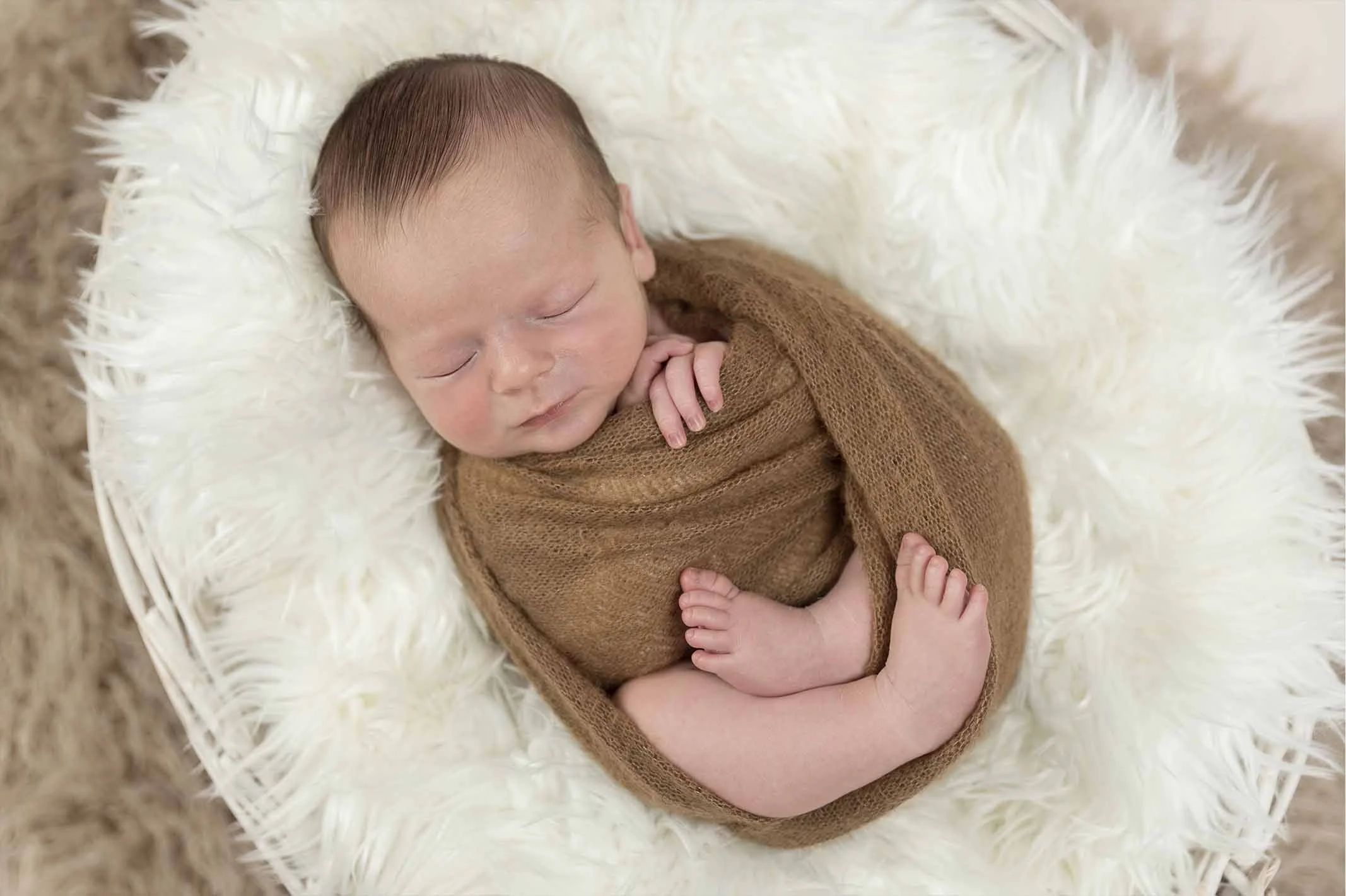 newborn in brown wrap for photoshoot