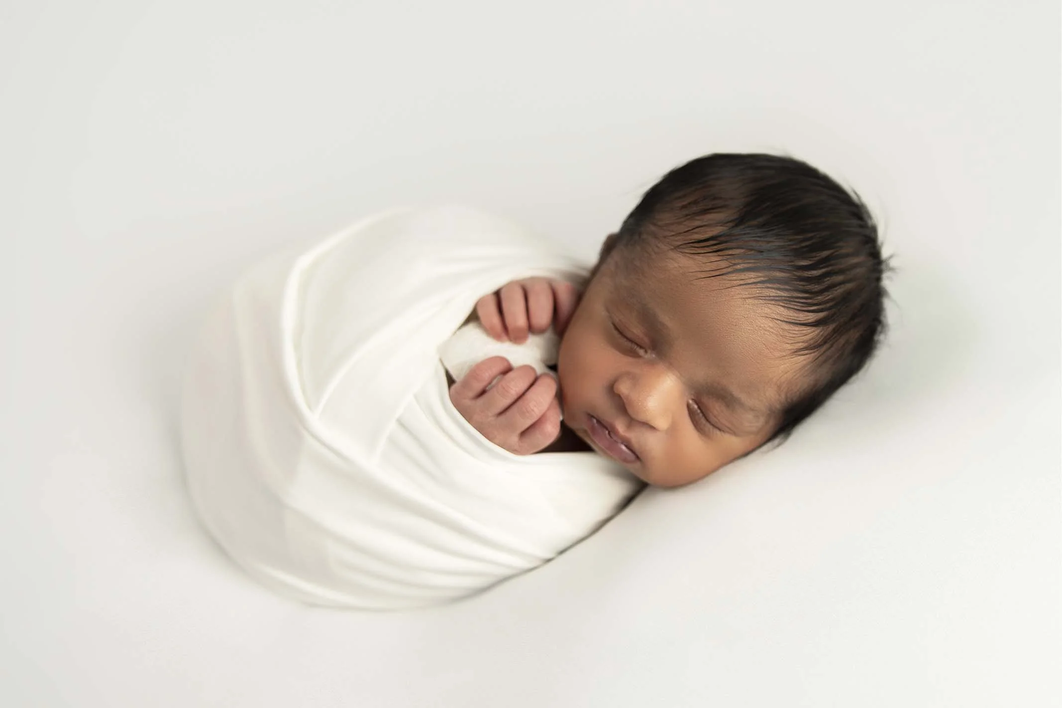 newborn in white wrap
